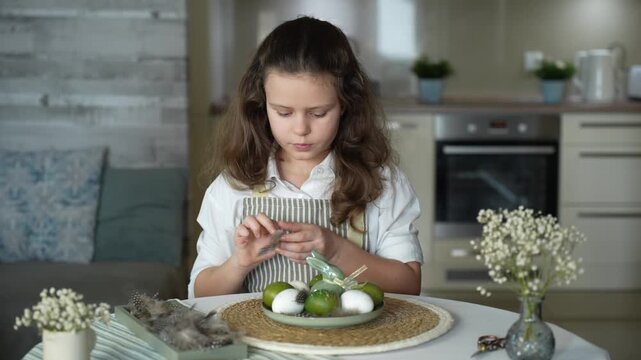 A girl decorating Easter eggs at home, preparing for a family holiday and a spring tradition