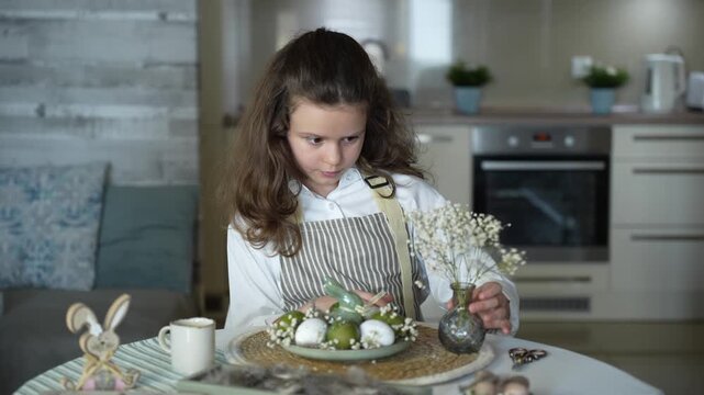 A girl decorating Easter eggs at home, preparing for a family holiday and a spring tradition