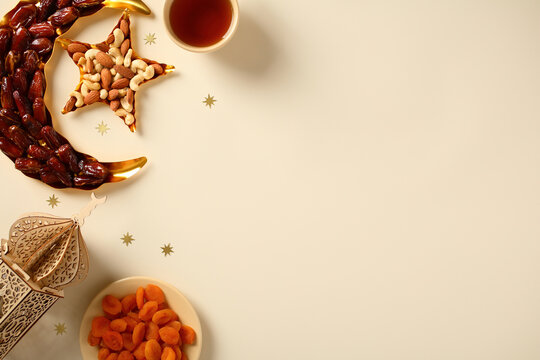 Ramadan concept with dates, nuts, apricots, tea, and lantern on light background with copy space.