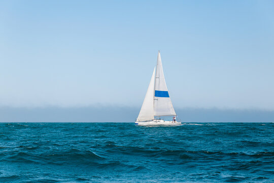 Sailboat Racing on the Open Sea With Blue Sails and Crew on a Sunny Day