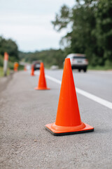 Traffic safety orange cones on roadside with blurred cars in background