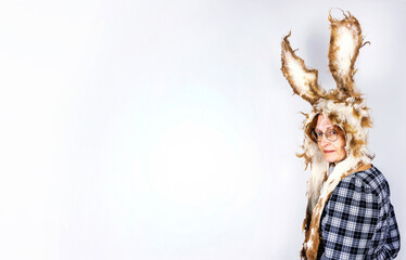Fototapeta premium Woman wearing felted wool bunny hat with long ears standing against a white wall with copy space