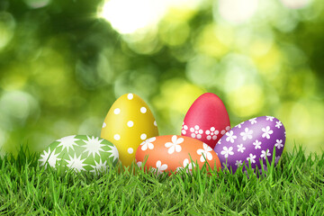Fototapeta premium Easter eggs in green grass against blurred background