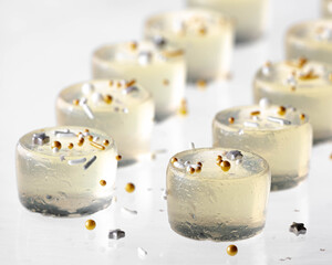 Champagne jelly shooters with festive sprinkles on a glass surface.