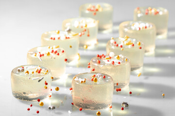 Champagne gelatin shooters with festive sprinkles against a light background.