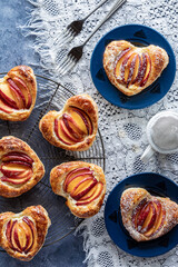 A top down view of delicious heart shaped peach pastries with powdered sugar.