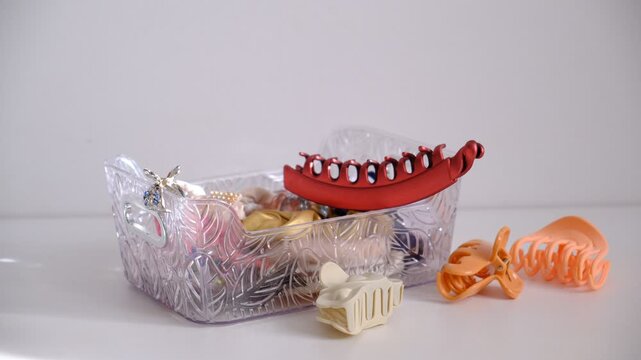 Woman hair accessories, plastic claw clips featuring multiple gripping prongs for securing hair, hair scrunchies falling in box. background with copy space. Trendy fashionable accessory. 