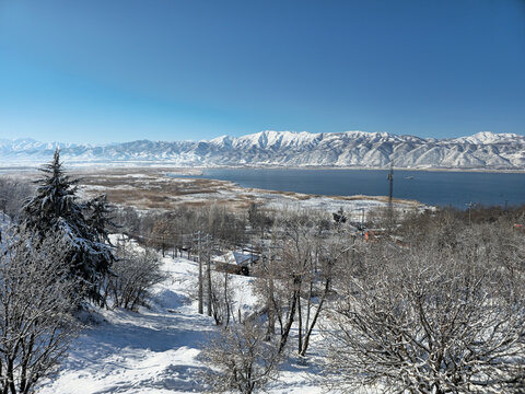 Winter lake surrounded by snowy trees and Zagros mountains under a clear blue sky, creating a peaceful and scenic natural landscape.  
📍Zaribar lake, Marivan