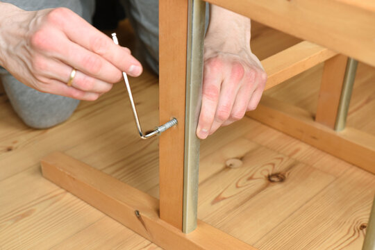 close up of a man using an allen key to build a chair 