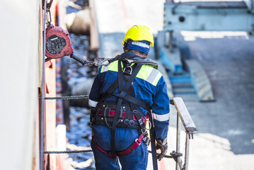 Fototapeta premium Seafarer in protective gear preparing a gangway after docking to ensure safe access to the vessel.
