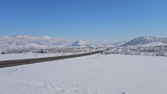 A long straight road stretches through a vast snowy winter landscape, flanked by majestic snow-covered mountains under a bright clear blue sky. Serene alpine tranquility.
📍Marivan, Kurdistan 