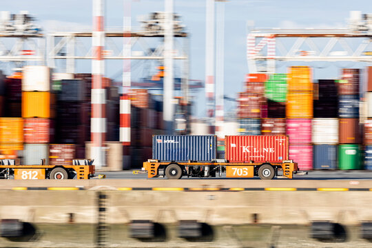 Panning shot of AGV carrying two containers on quay of large port terminal
