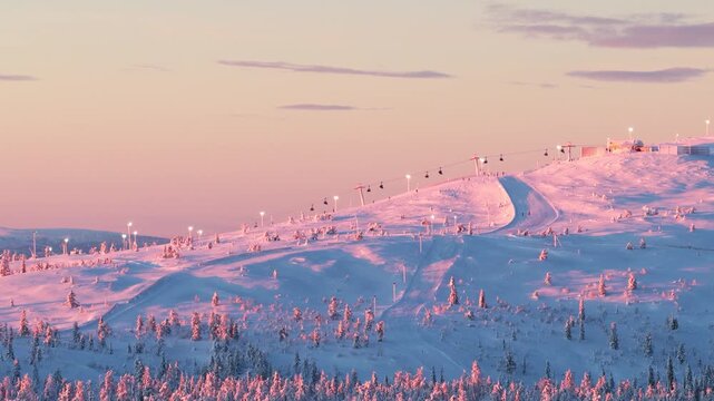 Drone Aerial of Ski Lifts Operating on Snowy Mountain at Winter Sunset in Lapland