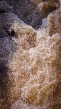 Aerial view of churning, muddy brown floodwater.