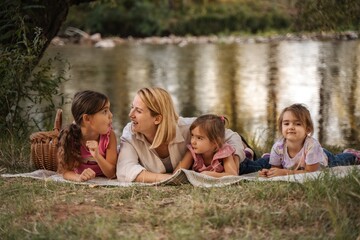 Fototapeta premium Mother and daughters enjoying a picnic by the river