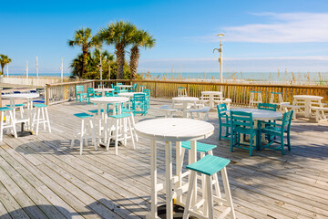 Fototapeta premium An empty beachfront cafe patio with palm trees along the sea grass and sand dunes of the Atlantic Ocean Grand Strand, at North Myrtle Beach, South Carolina.