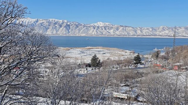 Winter lake surrounded by snowy trees and Zagros mountains under a clear blue sky, creating a peaceful and scenic natural landscape.  
📍Zaribar lake, Marivan