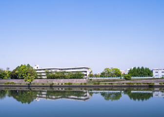 川面に映る学校と新緑の景色