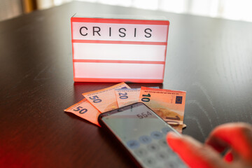 Crisis sign with euro money and a hand calculating finances