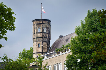 Detailed view of the historic Stapelhaus tower in Cologne's Old Town. Framed by green summer foliage at the Rheingarten park
