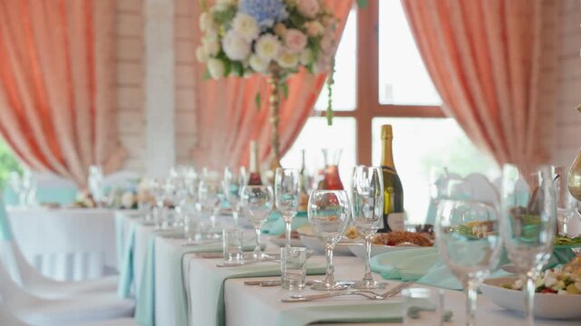 Beautifully arranged dining table set for an elegant occasion. Fresh flowers adorn the scene with delicate glassware and a bottle of champagne. Soft natural lighting enhances the elegant atmosphere.