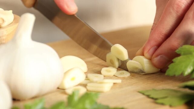 Woman cutting fresh garlic at table, closeup