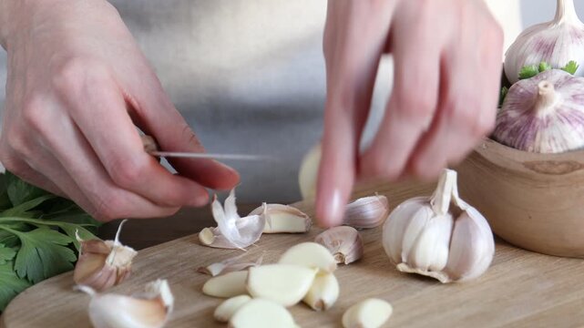 Woman peeling fresh garlic at wooden table, closeup