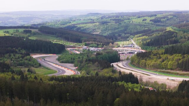 belgium f1 formula one circuit cuts through rolling ardennes hills asphalt bends eau rouge forest canopies run off zones distant countryside belgian grand around spa francorchamps 