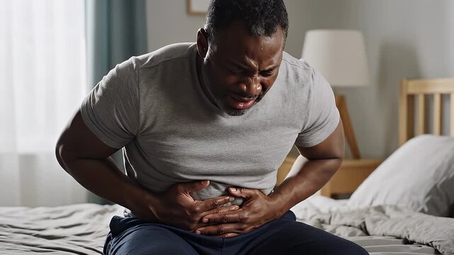 Video of man clutching stomach in pain at home.