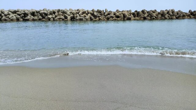 東北・日本海の海岸風景 砂浜に並ぶ沢山の波消しブロックと打ち寄せる波（山形県・庄内地方）