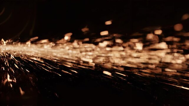 Percikan emas beterbangan di udara gelap dalam gerakan dinamis.