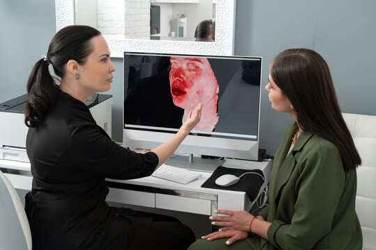 Cosmetologist showing female patient results of 3d picture of her face. Preperation for cosmetology procedure