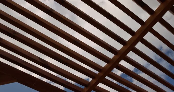 a wooden frame made of logs and planks on the beach in sunny weather against a blue sky with clouds, part of a wooden frame building