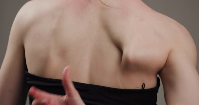 Close-up of a woman's bare back with a hand gesture creating a sense of gentle movement