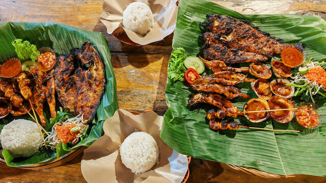 Indonesian Grilled Seafood Feast with Fish Prawns and Rice on Banana Leaves