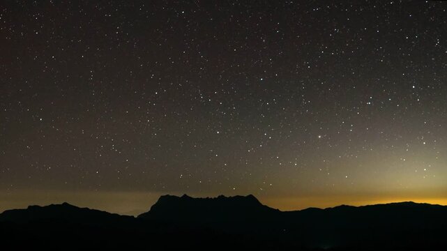 A celestial panorama of the night sky, studded with countless stars, casts a serene spell over the silhouette of a mountain range. The vastness of the cosmos, hinting at mysteries untold. Timelapse 