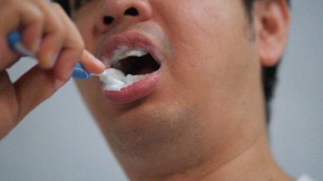 The man brushes his teeth with toothbrush with toothpaste close-up.