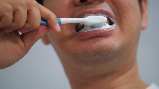 The man brushes his teeth with toothbrush with toothpaste close-up.