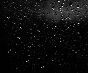 Fototapeta premium A dark textured background featuring numerous water droplets clinging to a glossy black surface high-quality