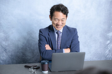 パソコンを見て会社の業績が改善して喜ぶ経営者や笑顔のスーツを着た社長のビジネスシーン