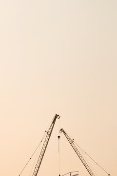 A tall construction crane and an orange sky background.