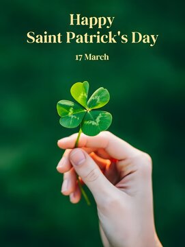 A hand holding a four-leaf clover with a green background and happy saint patrick's day text