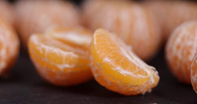 sliced peeled orange tangerine on a black slate table, ripe orange small mandarin without peel on a black slate board, tangerine divided into small slices