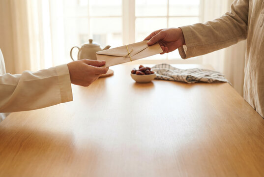 Man Handing Gift Envelope To Woman During Eid Celebration