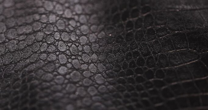 black artificial fabric in the style of crocodile skin with specks and spots, a close-up of a piece of clothing made in the style of leather items made of artificial leather