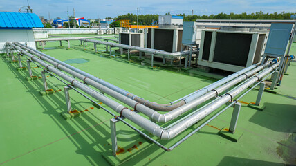 HVAC (Heating, Ventilation, and Air Conditioning) system installed on the rooftop of a building, with refrigerant pipes and electrical conduits connected