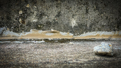 Grunge texture of a concrete wall with paint smudges, mold stains, and part of a concrete floor in horizontal orientation,