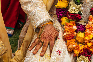 Close-up of Indian Groom's Henna-Decorated Hand and Traditional Sherwani garlands during a Hindu wedding ceremony