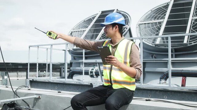 Two construction engineers in safety gear examine industrial HVAC units on rooftop, pointing and discussing project progress and setup.