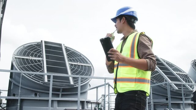 Two construction engineers in safety gear examine industrial HVAC units on rooftop, pointing and discussing project progress and setup.